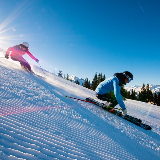 2 Skifahrer beim Early Morning Skiing auf der Piste in Dorfgastein